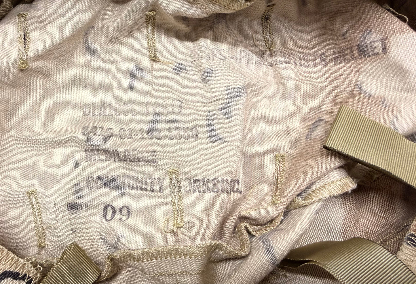 Close-up of a military helmet cover with text and markings.