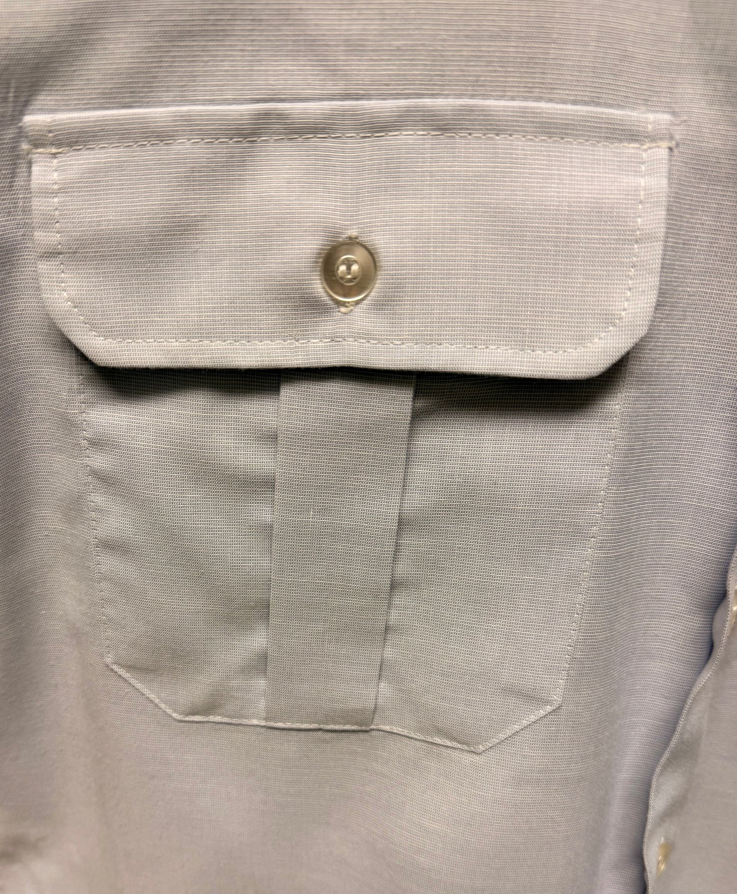 Close-up of a gray shirt with a button and pocket detail