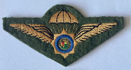 Embroidered badge with wings and a central emblem on a green background
