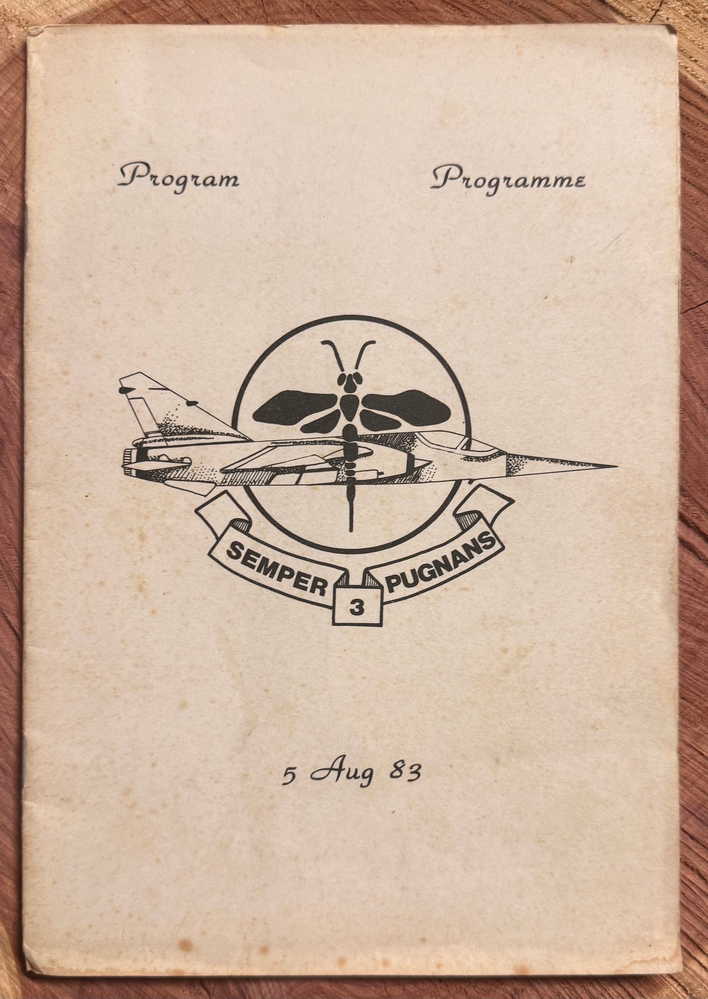 Vintage program book with military insignia and text on a wooden surface