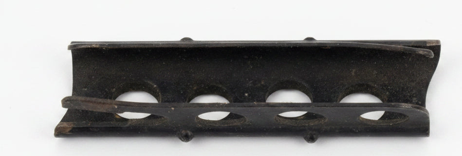 A black plastic curved component with four circular cutouts, shown on a light brown wooden surface.