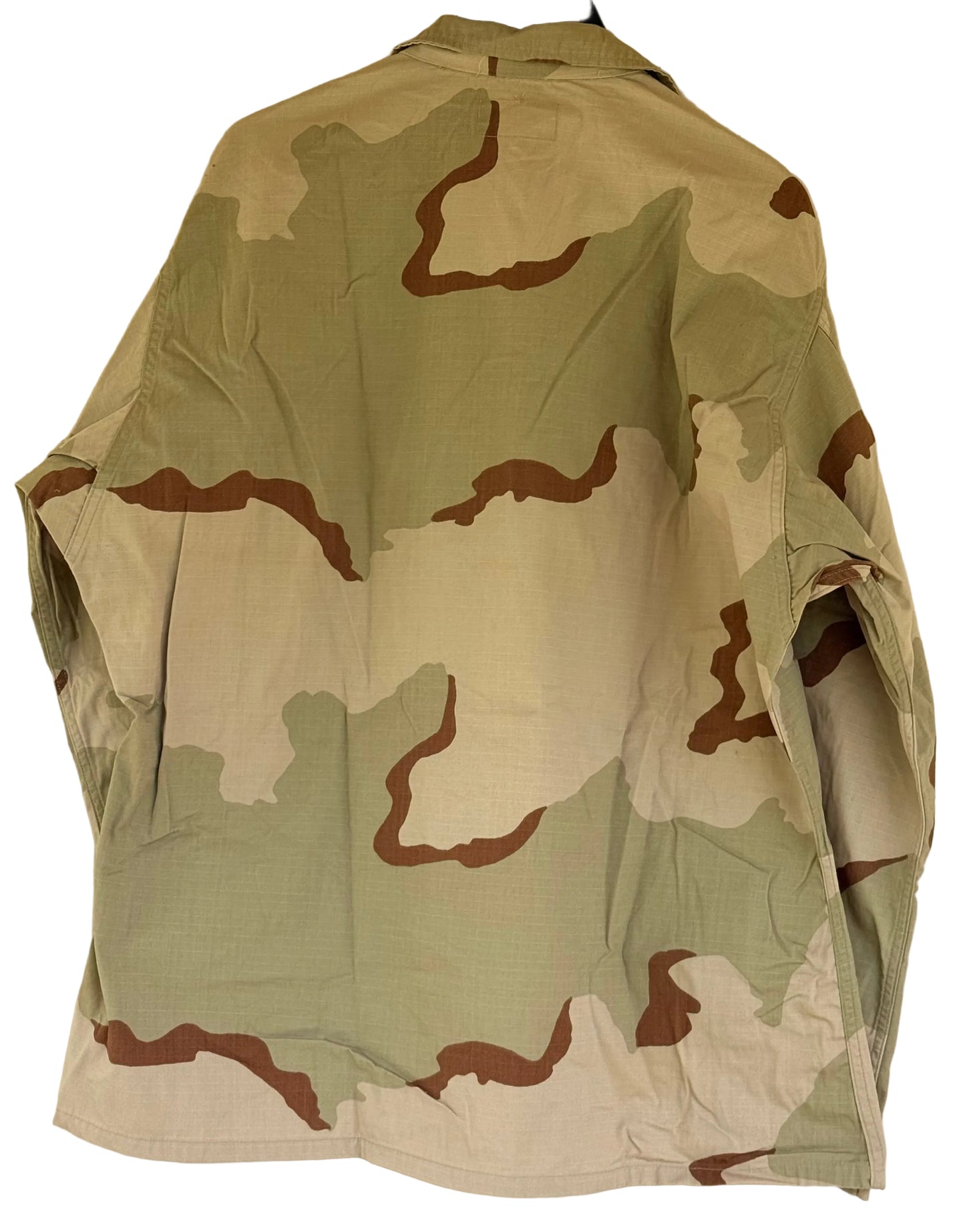 A military-style camouflage jacket hanging on a black hanger against a plain beige wall. The pattern features light sage green, tan, and brown shapes.
