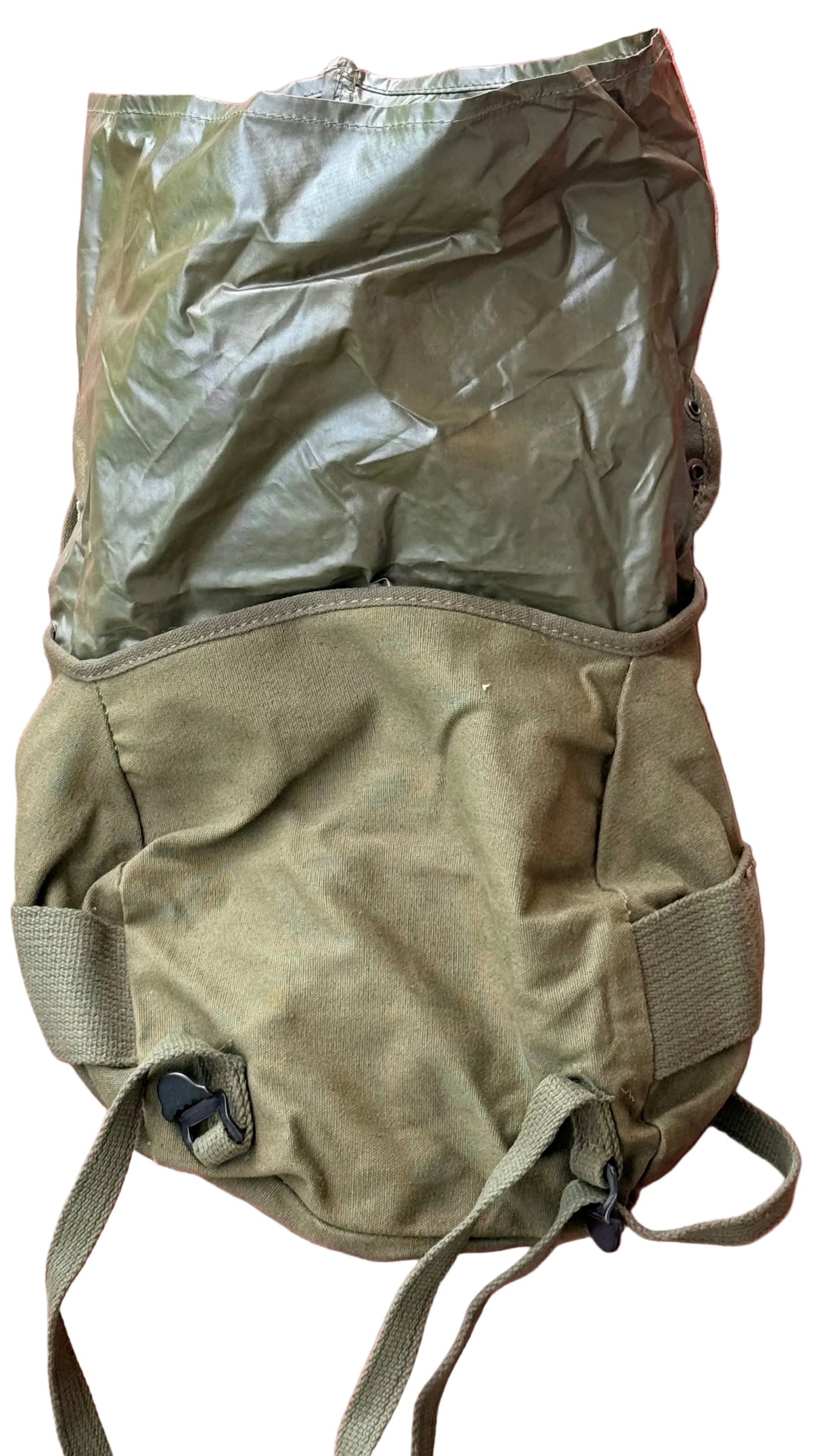 An olive green military-style canvas backpack or gear bag with a shiny olive plastic cover, laid flat against a textured pink background.