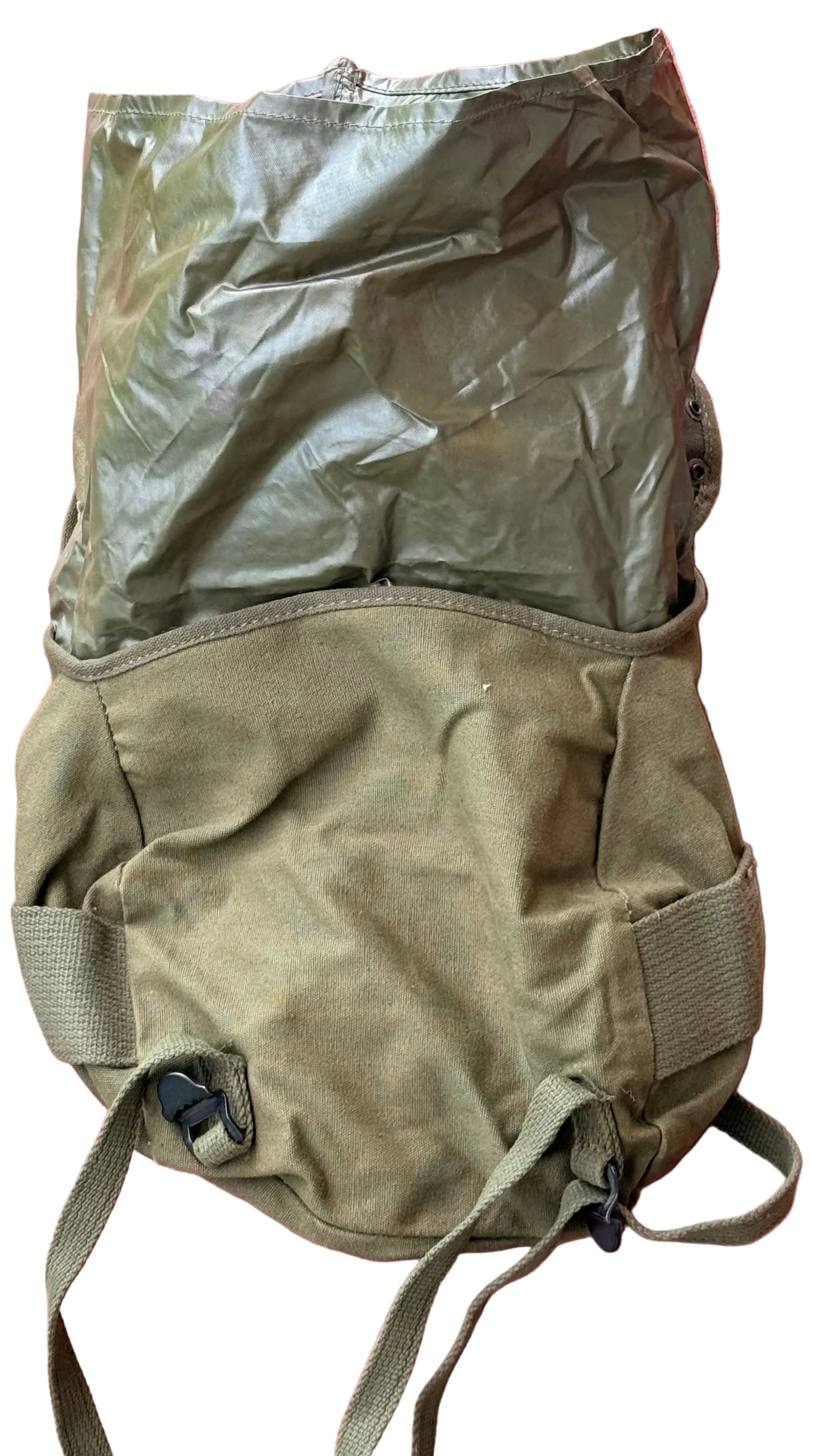 An olive green military-style canvas backpack or gear bag with a shiny olive plastic cover, laid flat against a textured pink background.