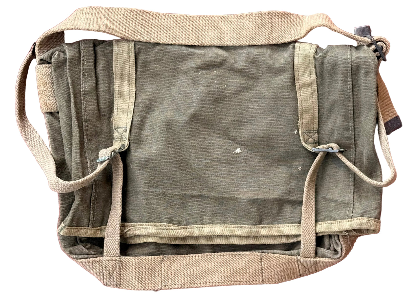 A vintage olive green canvas utility bag with beige webbing straps and trim, laid flat on a textured pink surface.