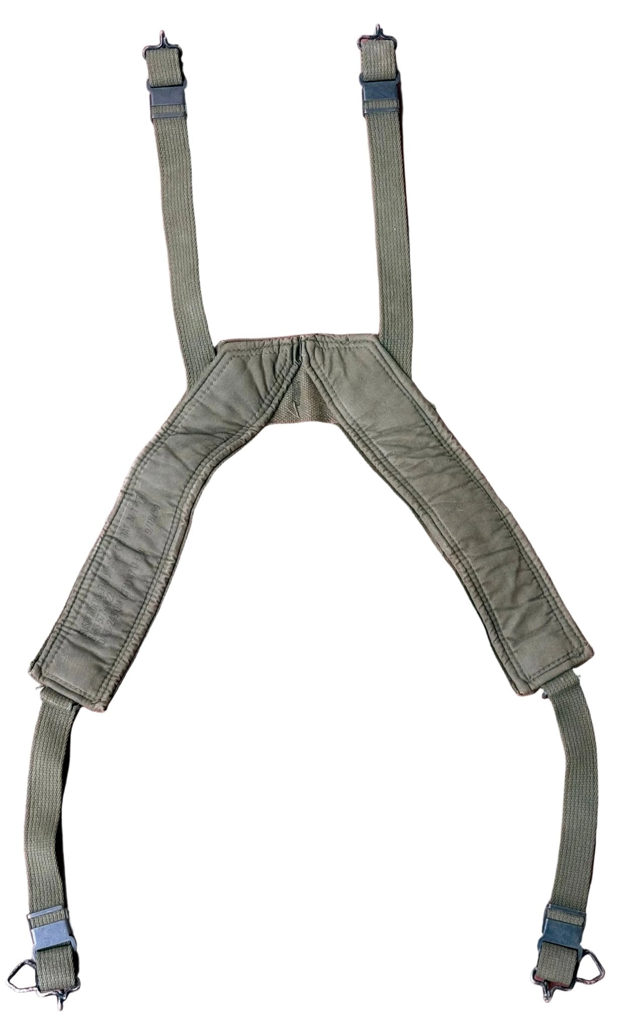 An olive green military-style web harness with padded shoulder straps and adjustable suspenders, laid flat on a textured pink surface.