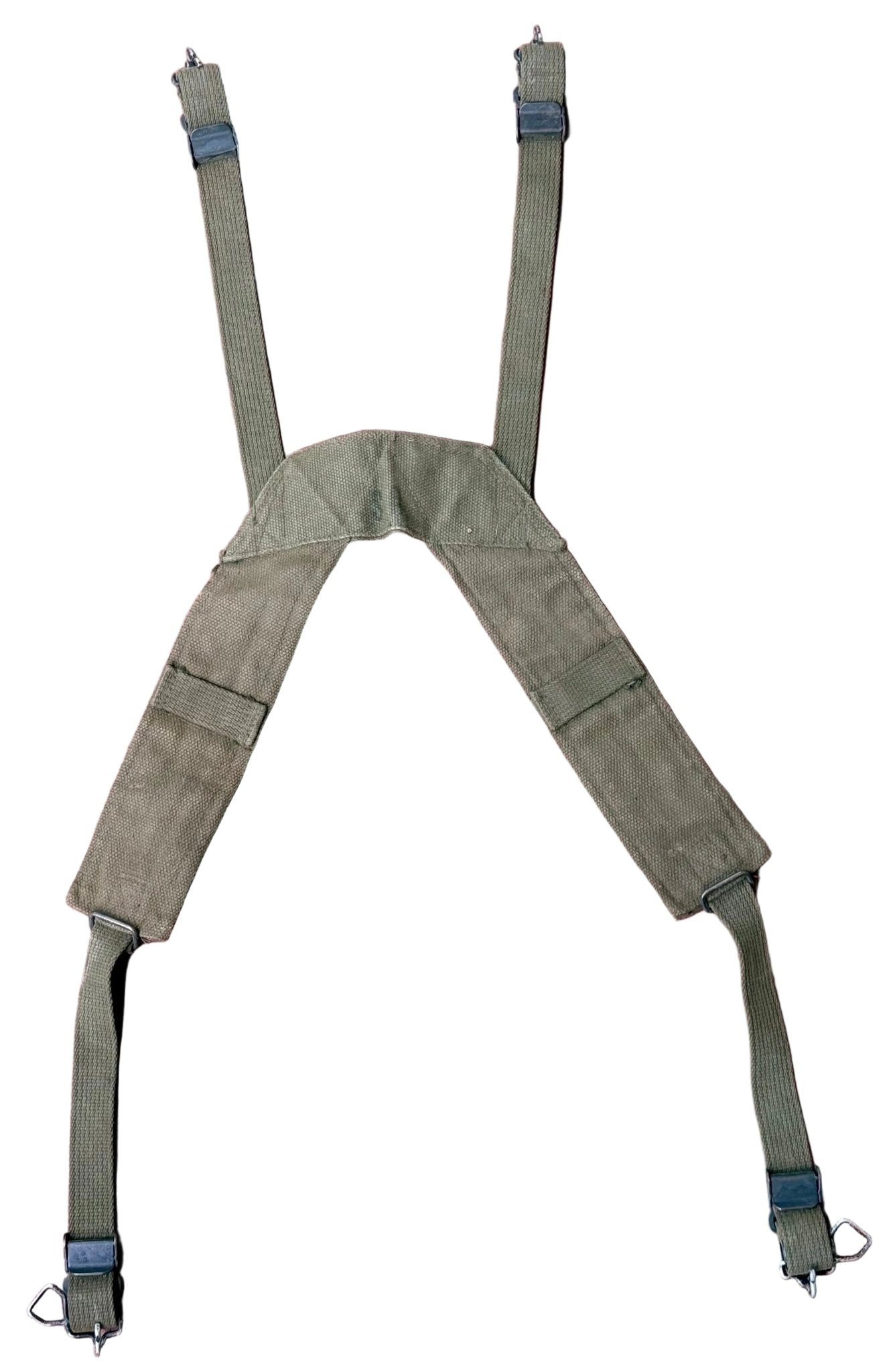An olive green military-style shoulder harness with adjustable straps and metal D-rings, laid flat on a textured reddish-pink surface.