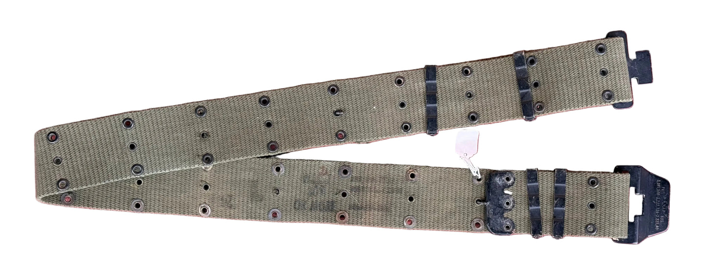 A khaki canvas utility belt with black plastic buckles and metal rivets, laid flat on a textured red surface.