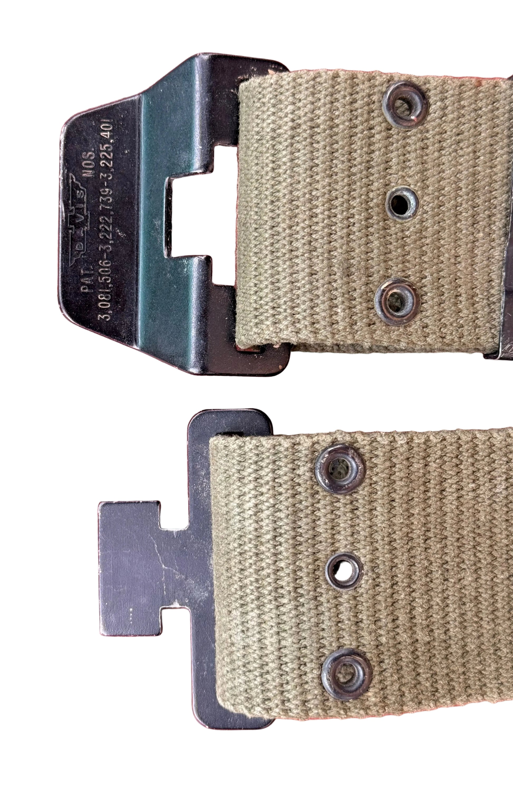 Close-up of a tan canvas strap with black metal hardware, including a buckle and rivets, laid on a textured red background.
