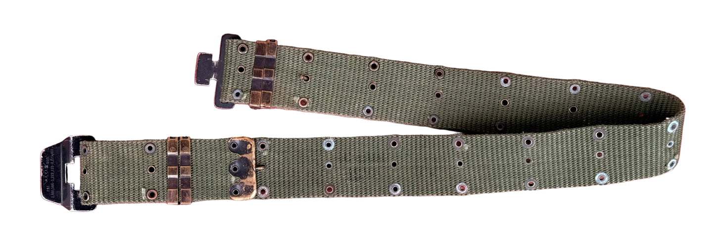 An olive green nylon utility belt with brass-toned metal rivets and black plastic buckle ends, laid flat on a textured red surface.