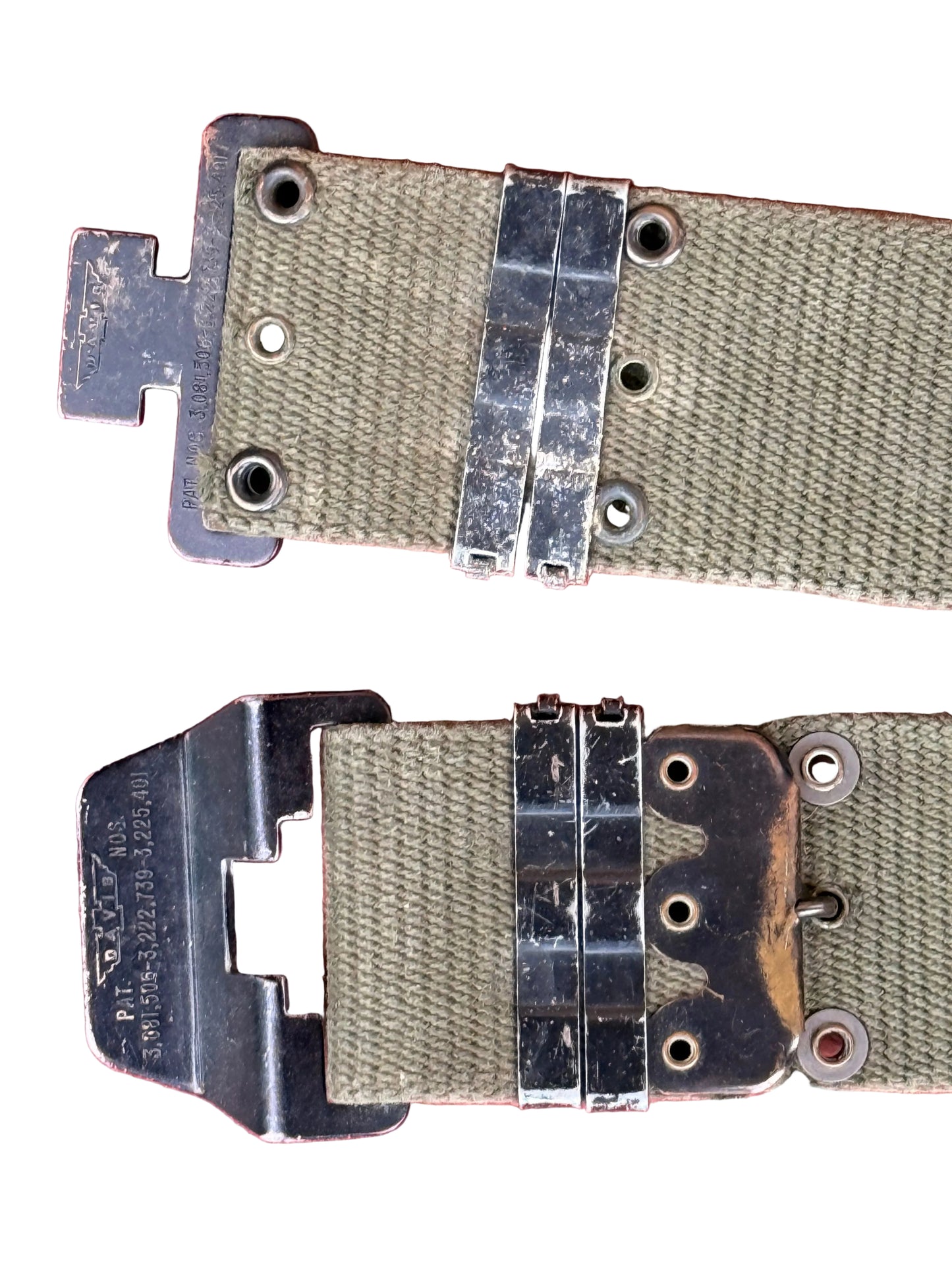 A close-up of a vintage olive green canvas strap with heavy-duty black metal hardware and a matching metal buckle, laid flat on a textured pink background.