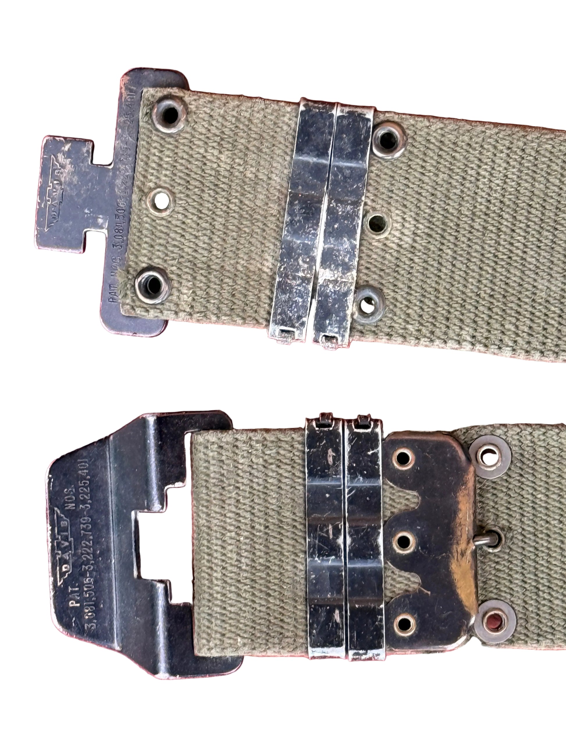 A close-up of a vintage olive green canvas strap with heavy-duty black metal hardware and a matching metal buckle, laid flat on a textured pink background.