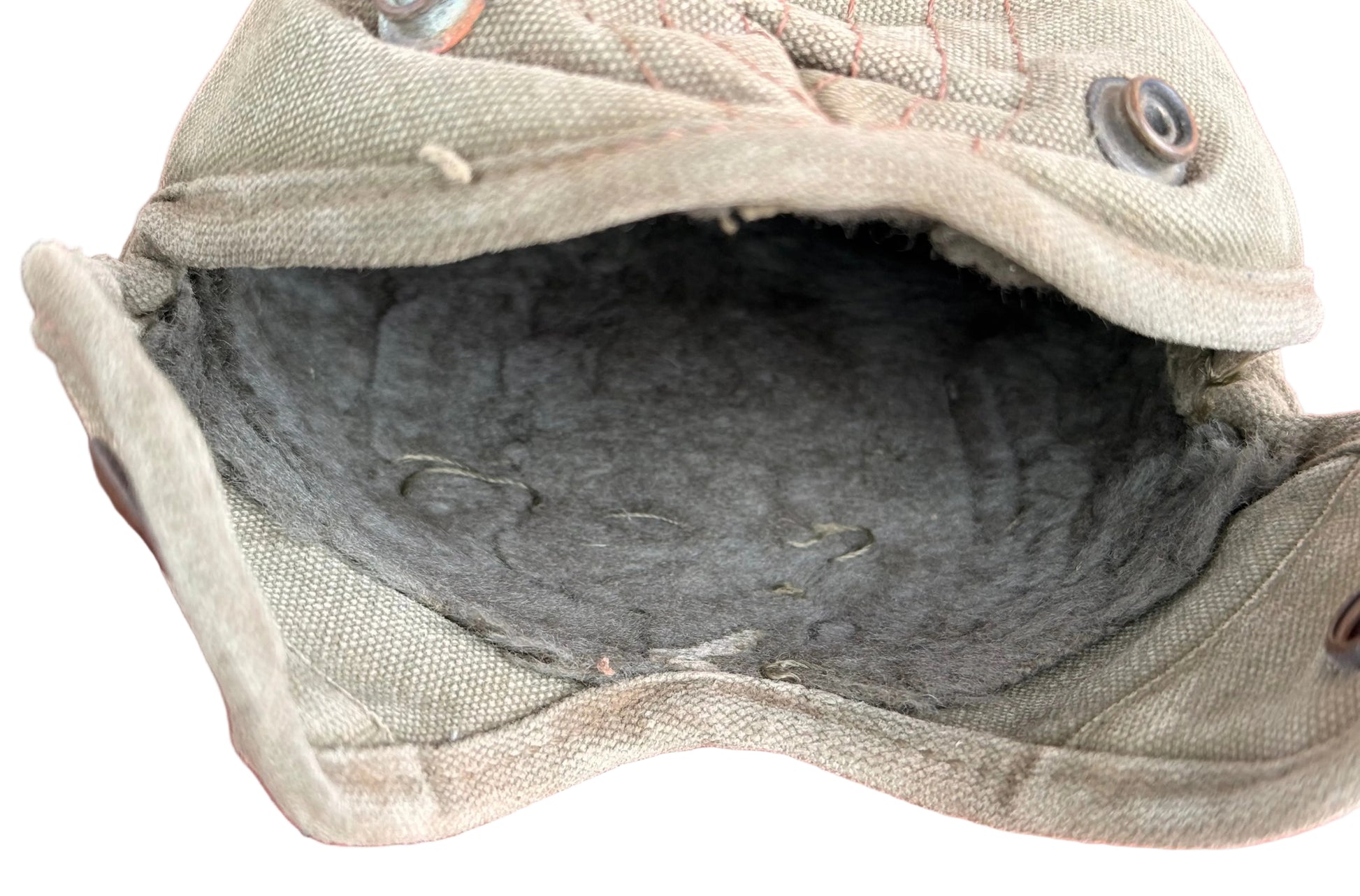 A close-up of a vintage canvas utility pouch with a dark gray felt lining, resting on a red textured surface.