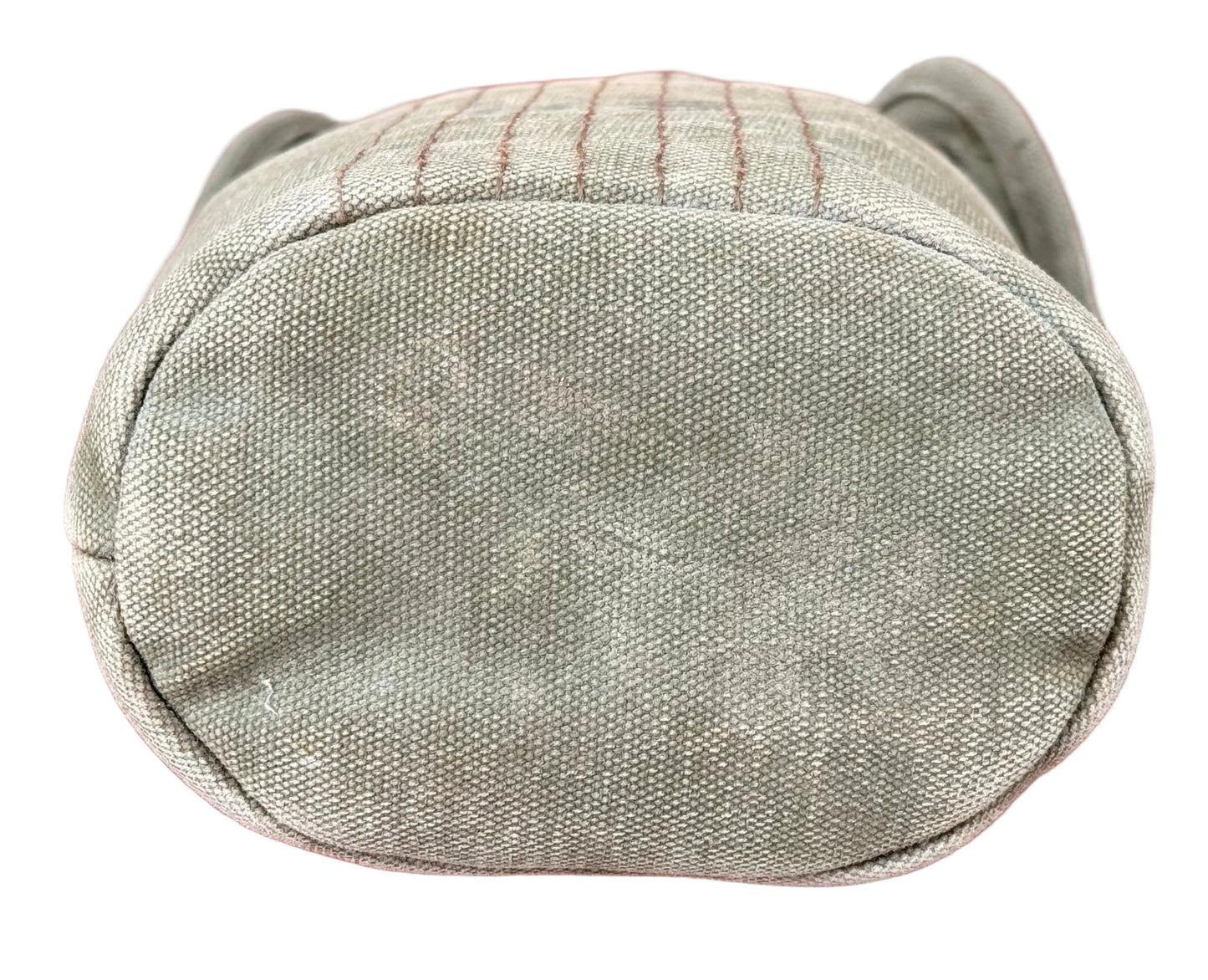 A close-up top-down view of a light olive green canvas pouch or bag with a stitched pattern, set against a textured reddish-pink background.