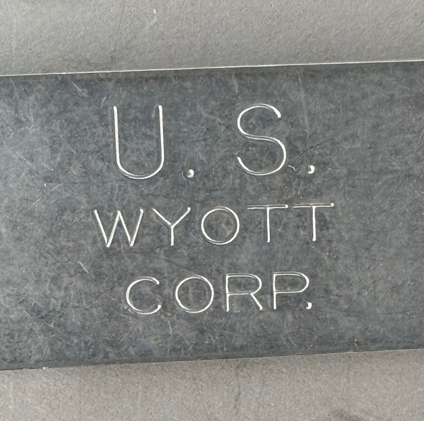 A close-up of a dark gray stone or metal plaque engraved with the text 'U.S.