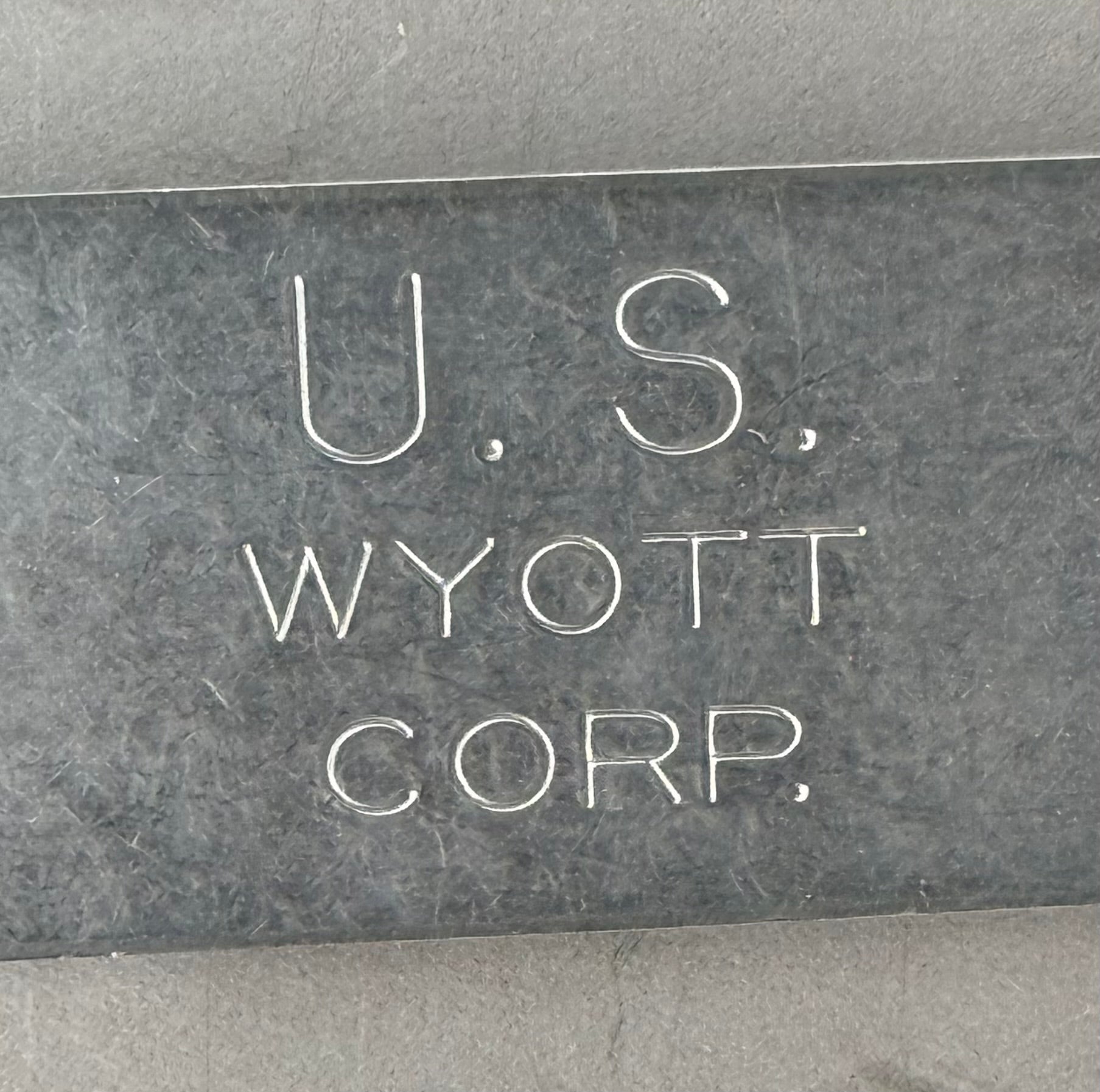 A close-up of a dark gray stone or metal plaque engraved with the text 'U.S.