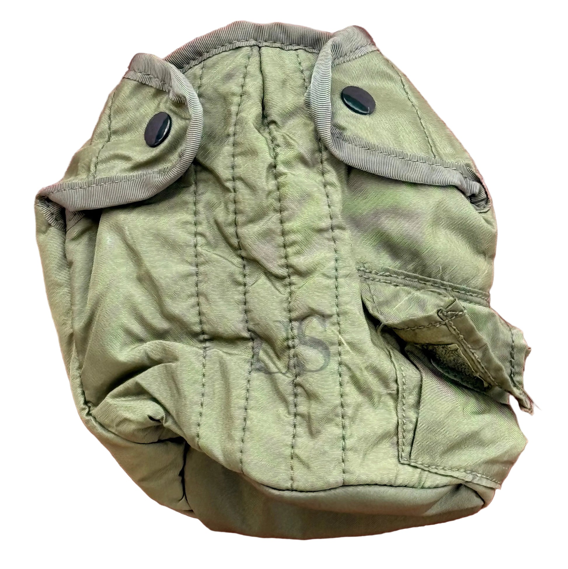 An olive green military-style quilted pouch with snap closures and a zippered pocket, laid flat on a textured pink surface.