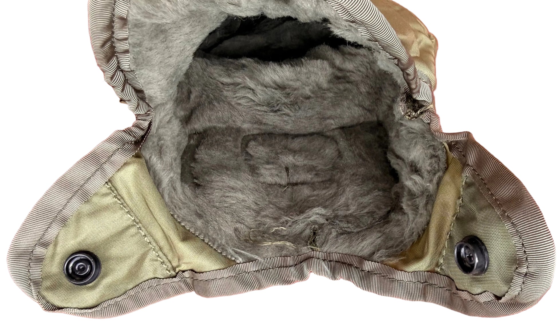 A close-up of a vintage winter hat or hood, showing the interior lining with gray faux fur and olive green fabric panels with snap buttons, set against a textured red background.