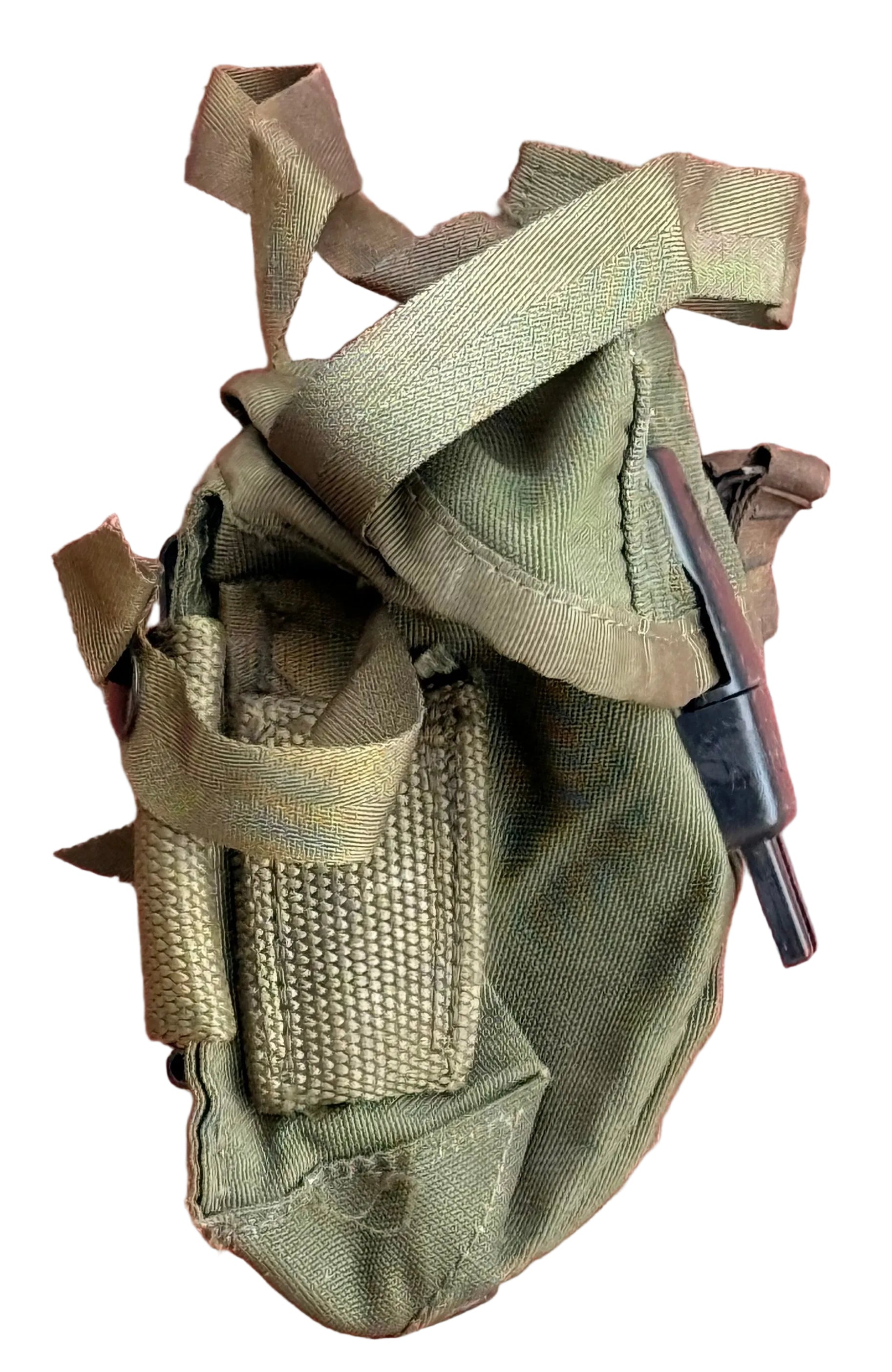 An olive drab green canvas pouch with webbing straps and a black plastic tool or attachment, laid flat against a textured red background.