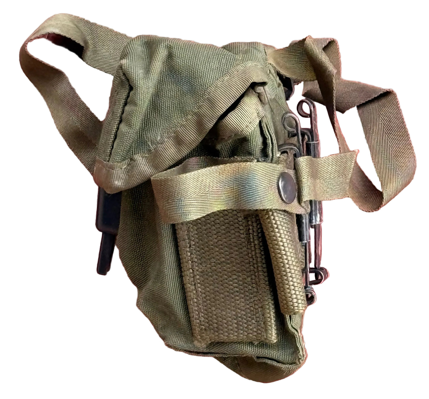 An olive green tactical pouch with a webbed strap and a front flap pocket, shown against a textured red-pink stucco wall.