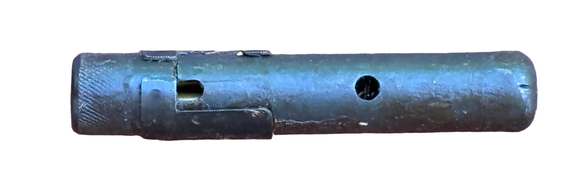 A dark metallic cylindrical component, possibly a mechanical part or tool fragment, lying horizontally on a textured pink surface.