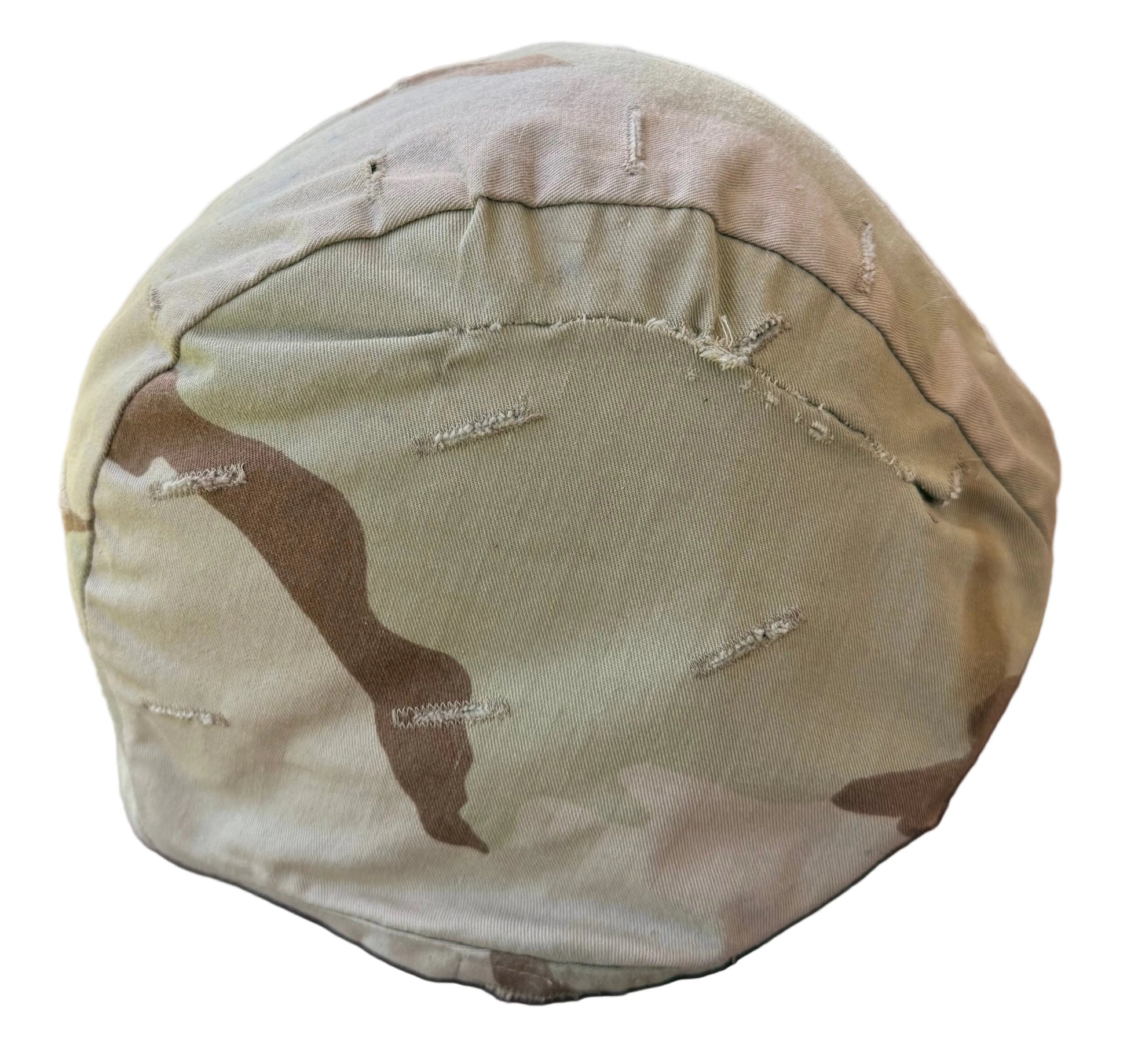 A close-up of a camouflage fabric-covered round object, likely a cushion or padded accessory, resting on a reddish-brown surface.