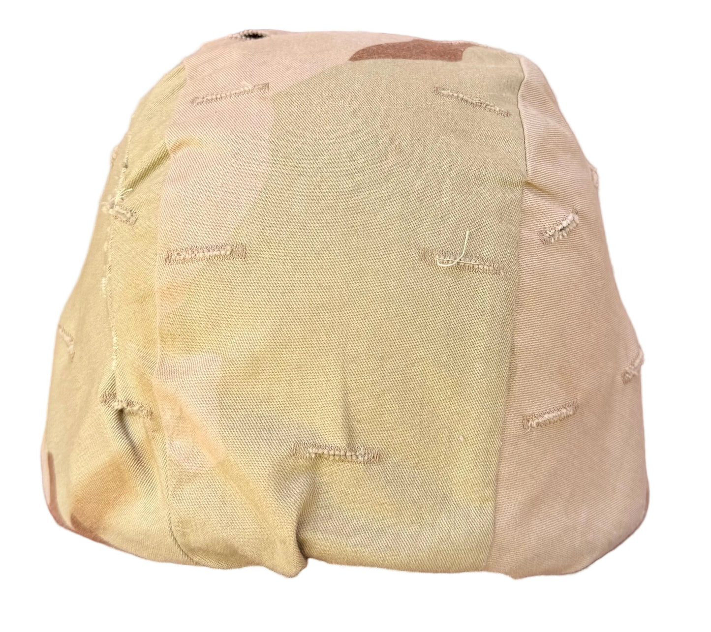 A beige fabric-covered object with visible seams and small metallic stitched details, photographed on a reddish-brown surface.