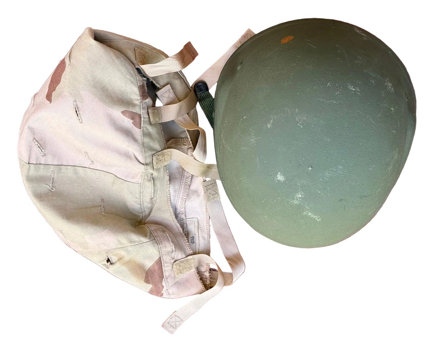 A vintage olive green military helmet and a matching desert camouflage canvas backpack laid flat on a textured pink surface.