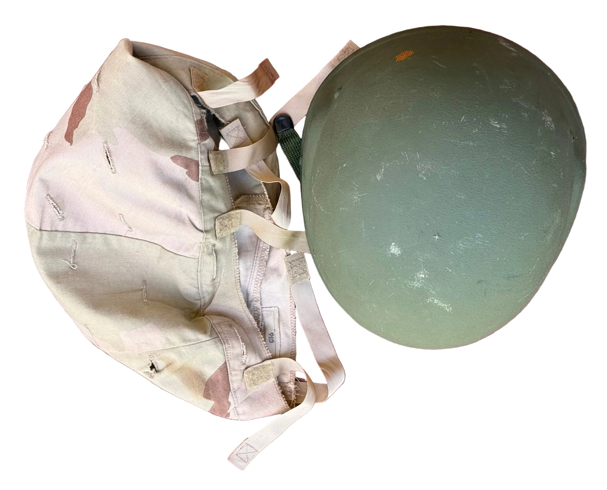 A vintage olive green military helmet and a matching desert camouflage canvas backpack laid flat on a textured pink surface.
