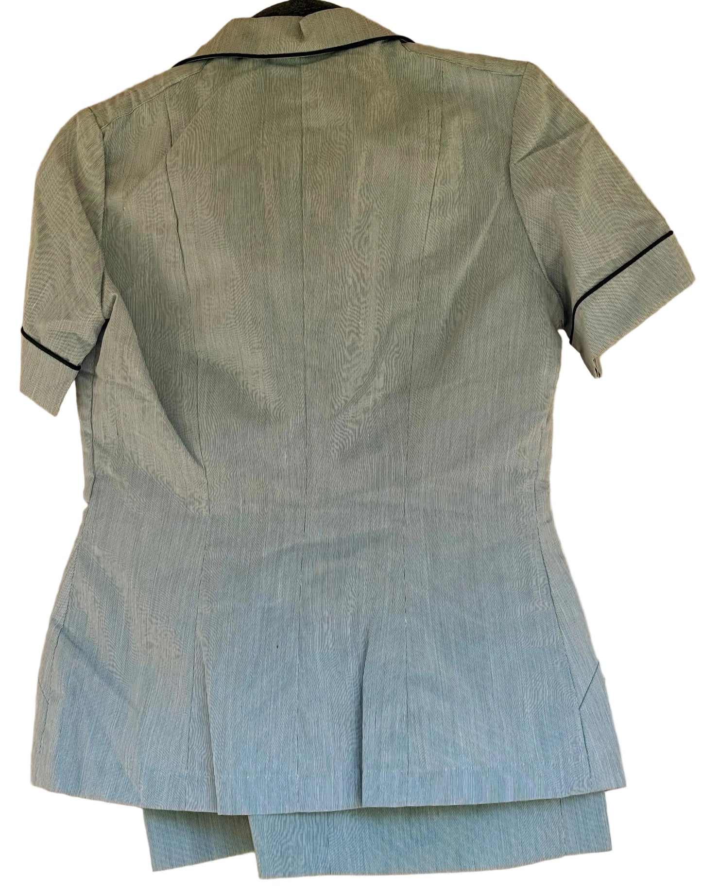 A light blue textured short-sleeve top or jacket with black piping trim along the collar and sleeve cuffs, shown hanging against a beige wall.