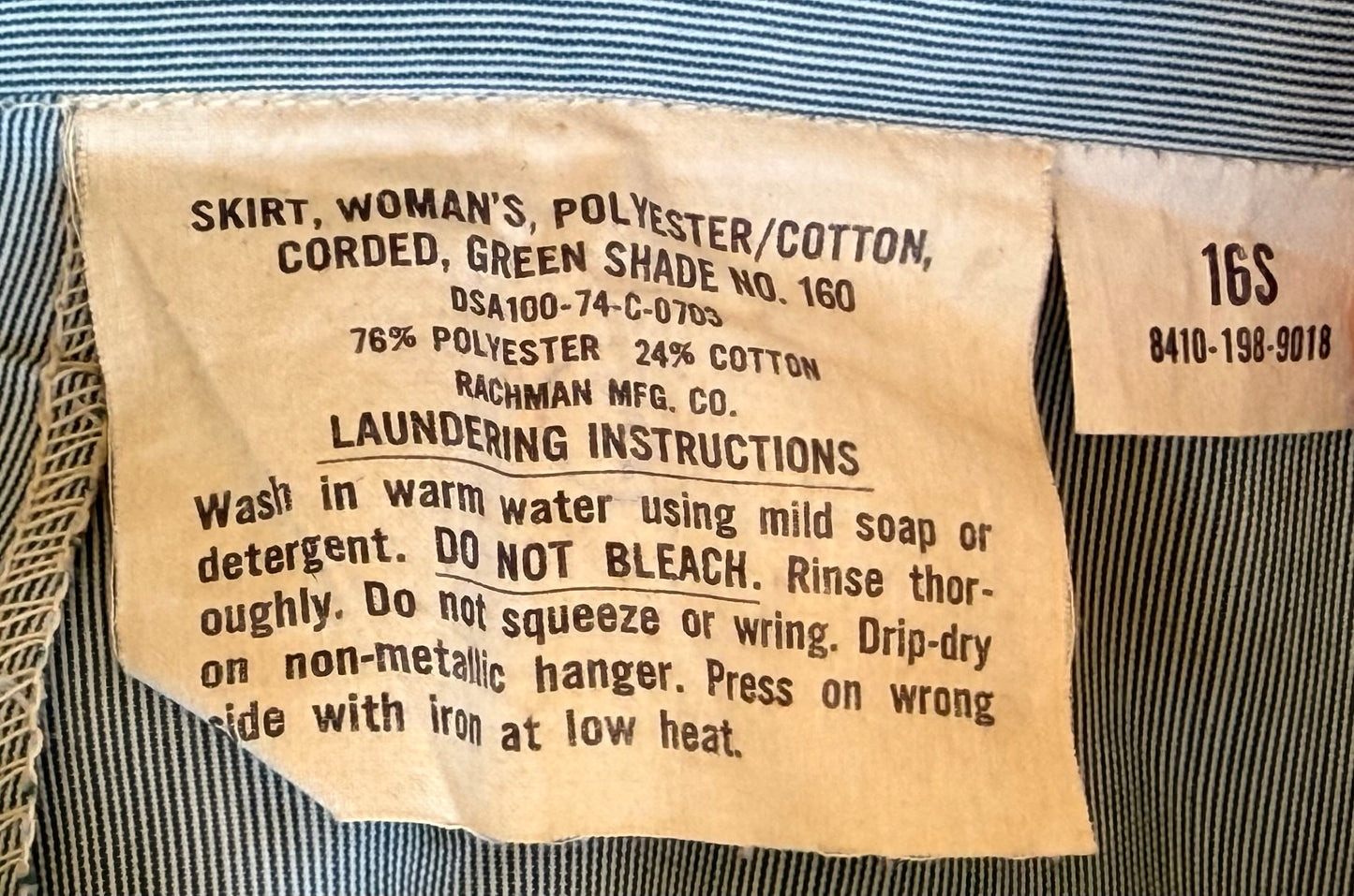 Vintage interior label of a women's skirt made of polyester/cotton blend, showing size 16S and laundering instructions in black text on a beige paper tag.