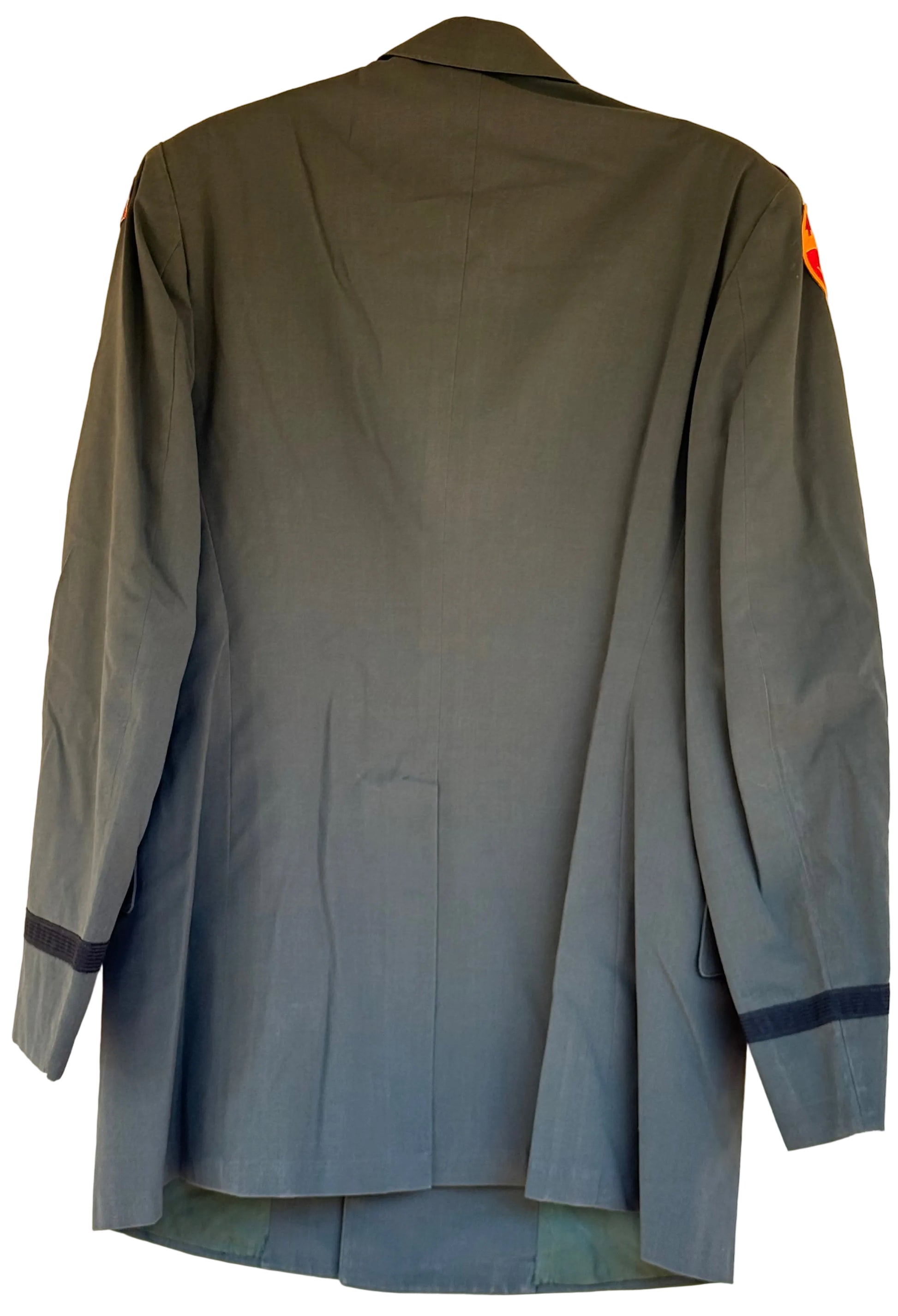 A dark olive green military-style jacket shown from the back, hanging against a plain beige wall. It features dark navy blue bands on the cuffs and a small orange-red insignia on the left shoulder.