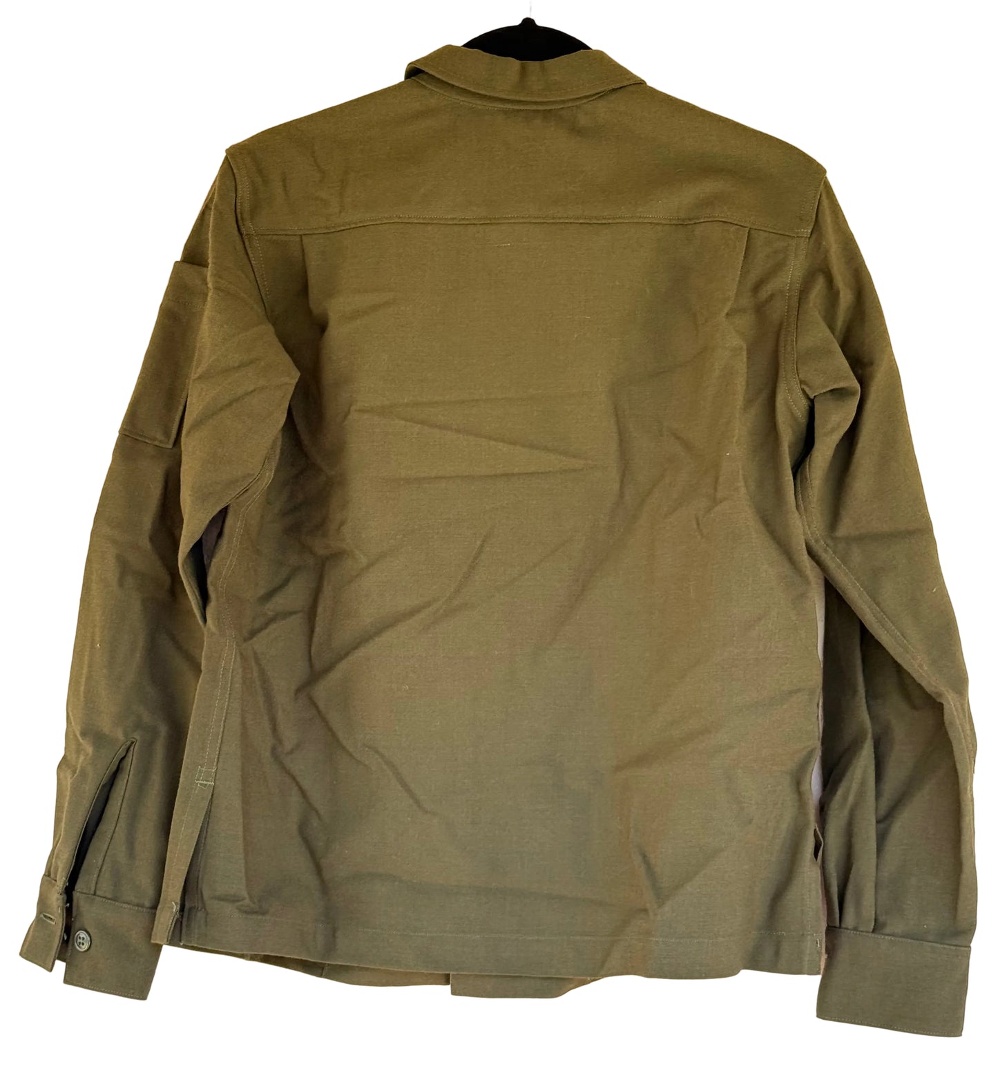 An olive green military-style jacket hanging on a black hanger against a textured beige wall, showing the back view with long sleeves and side pockets.