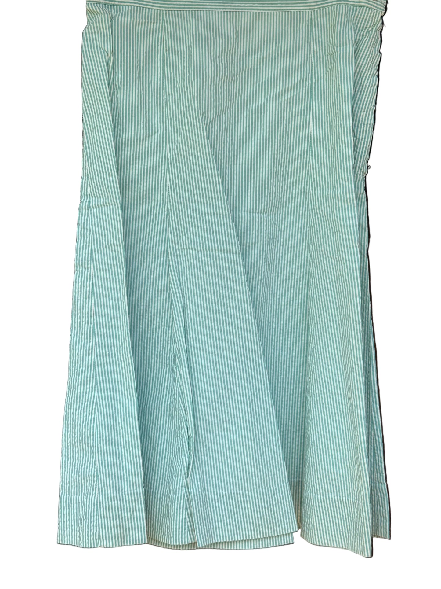 A light mint green and white vertically striped skirt hanging against a dark brown wooden background.
