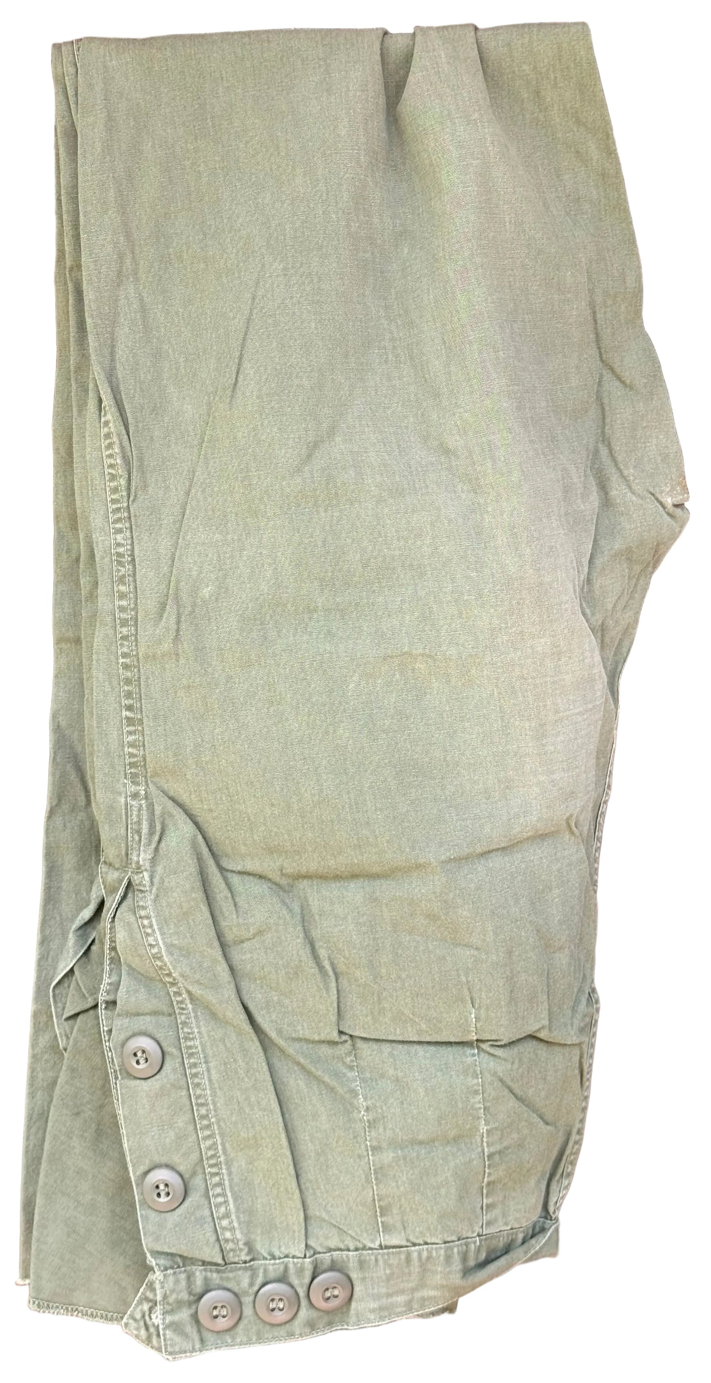 A pair of light olive green cargo pants laid flat on a dark wooden surface, featuring buttoned cuffs and side pockets.