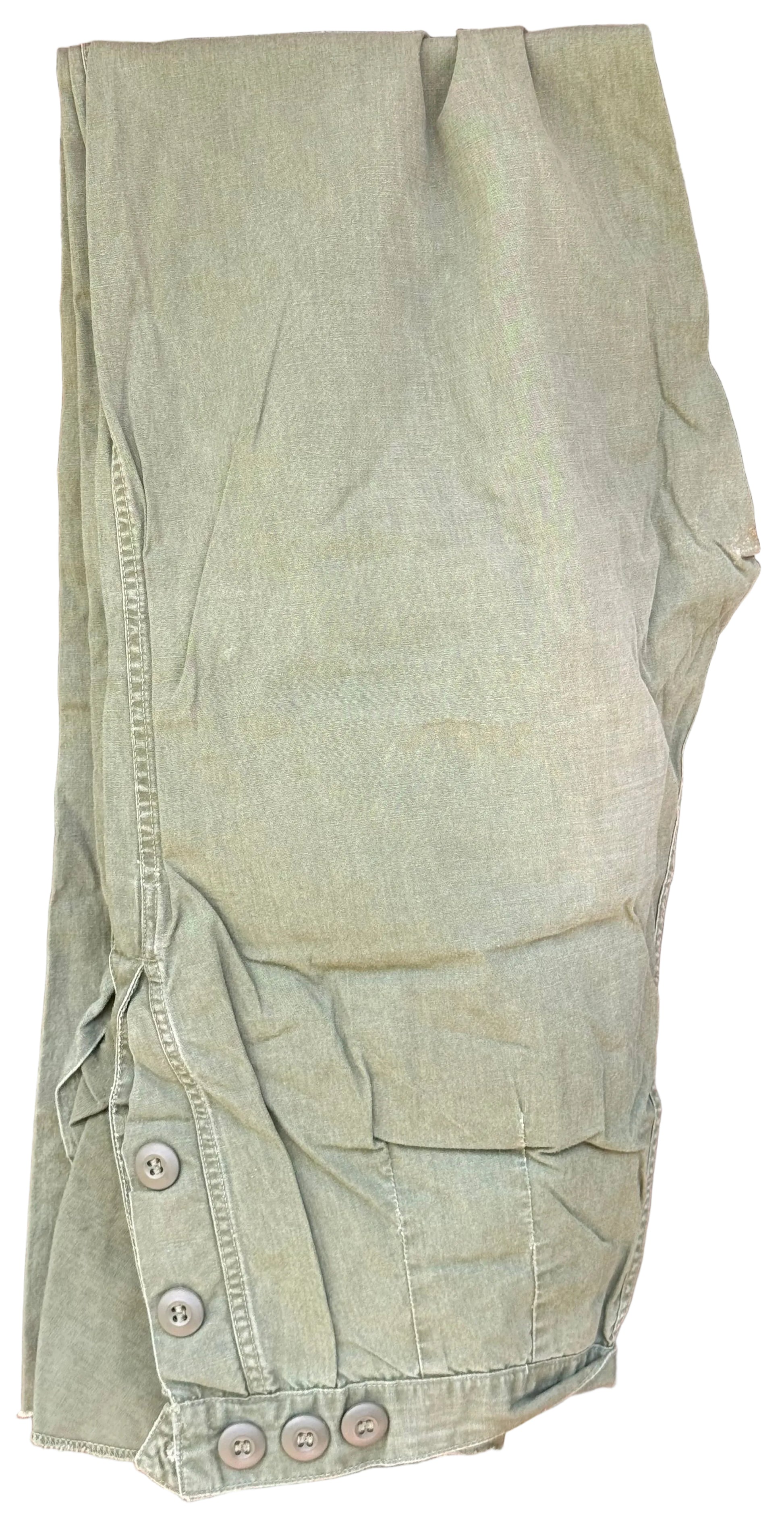 A pair of light olive green cargo pants laid flat on a dark wooden surface, featuring buttoned cuffs and side pockets.