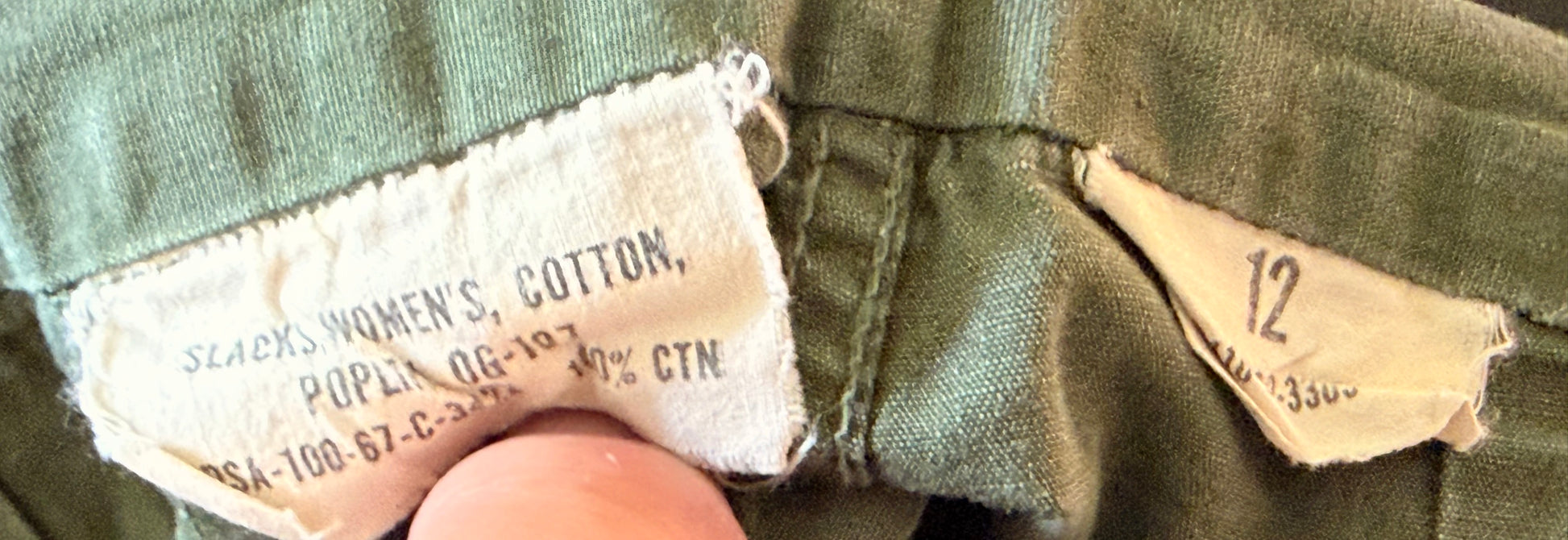 Close-up of a vintage olive green garment's inner waistband showing a cotton brand label that reads 'Sears Women's Cotton' and a size marker indicating '12'.