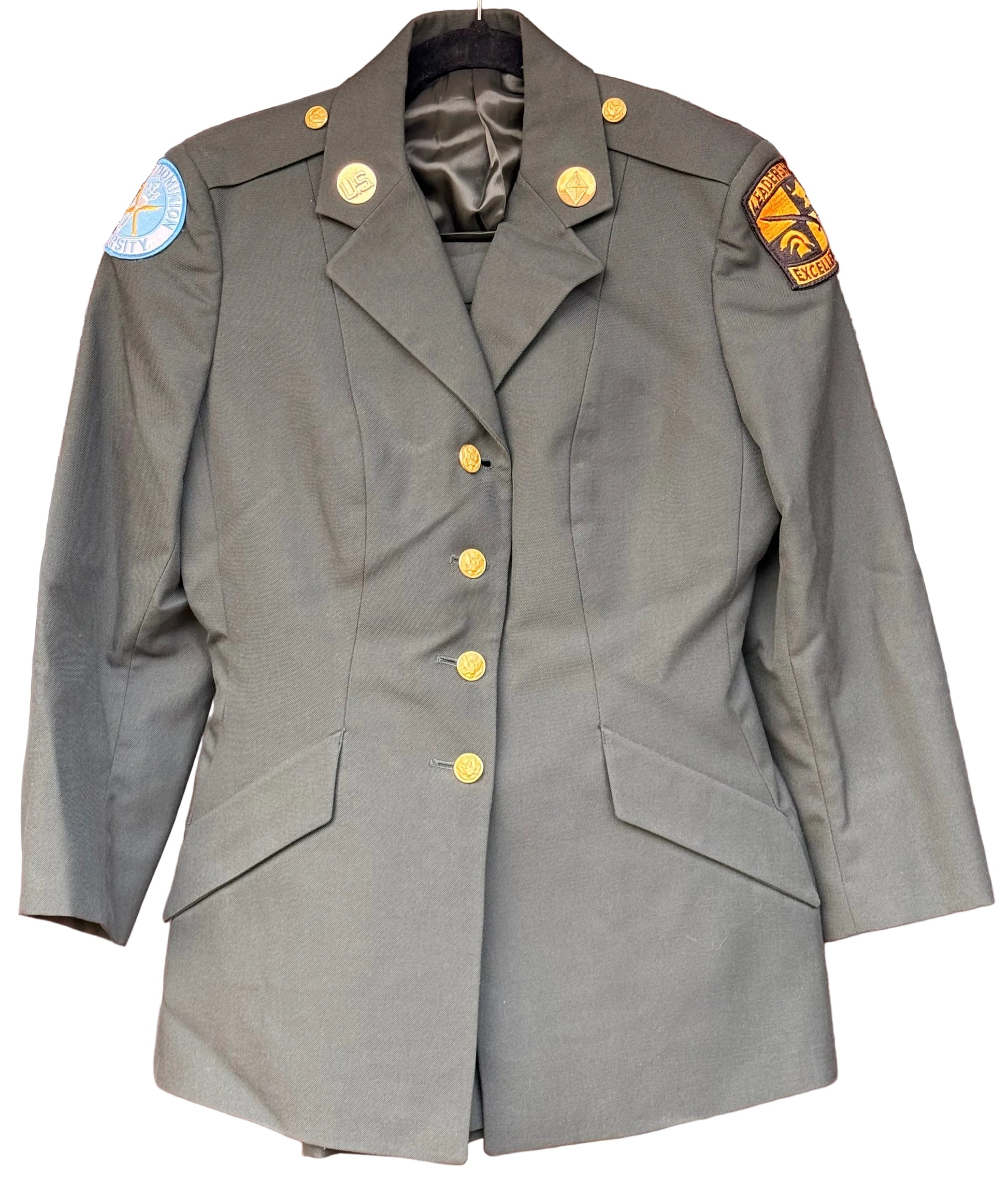 An olive drab military-style blazer jacket with gold buttons, displayed on a hanger against a carved wooden background. It features shoulder patches, one of which reads '101st Airborne Division'.