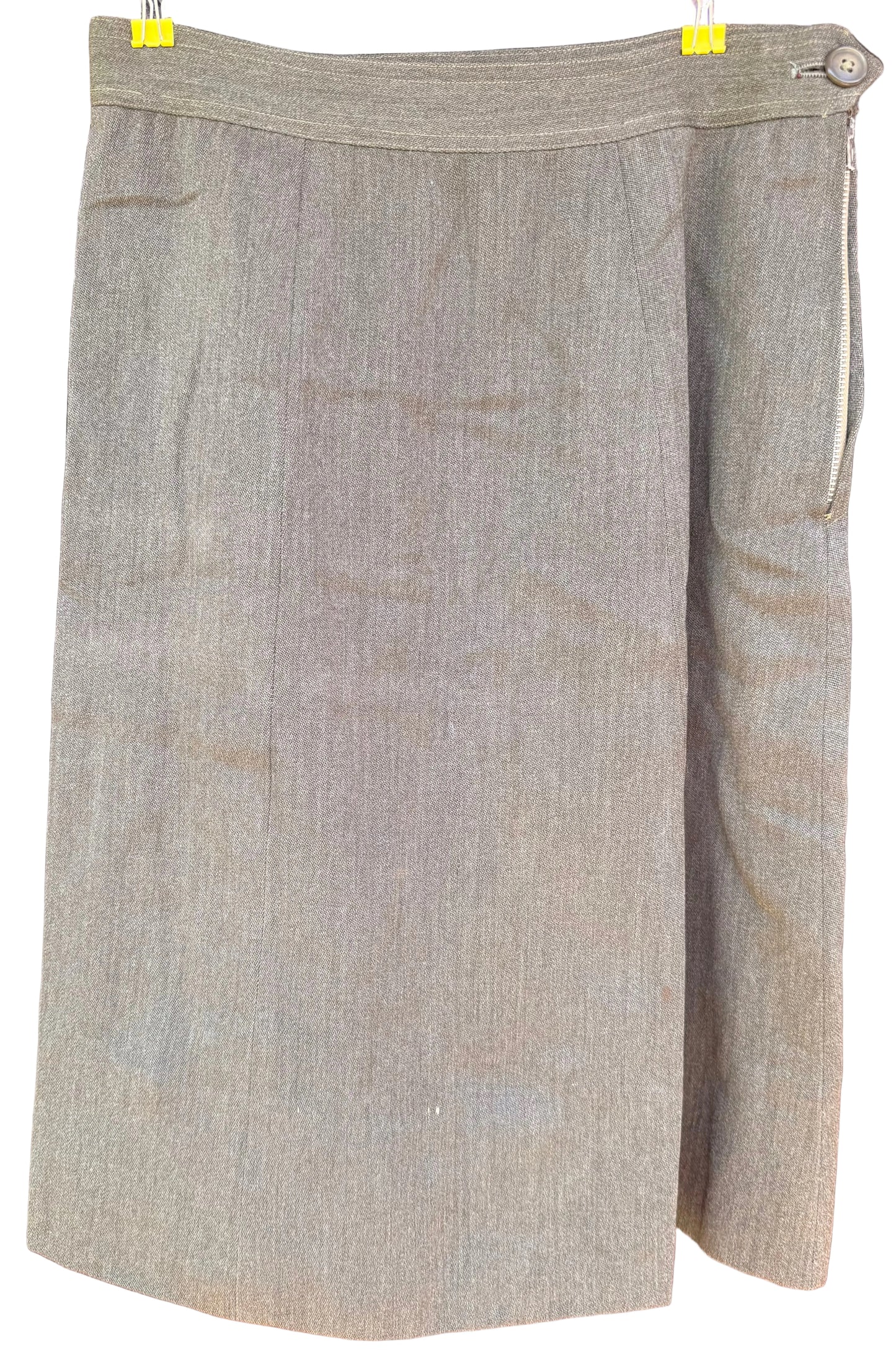 A taupe-beige textured skirt with a wrap-style front and side button closure, hanging on a black hanger against a dark wood background.