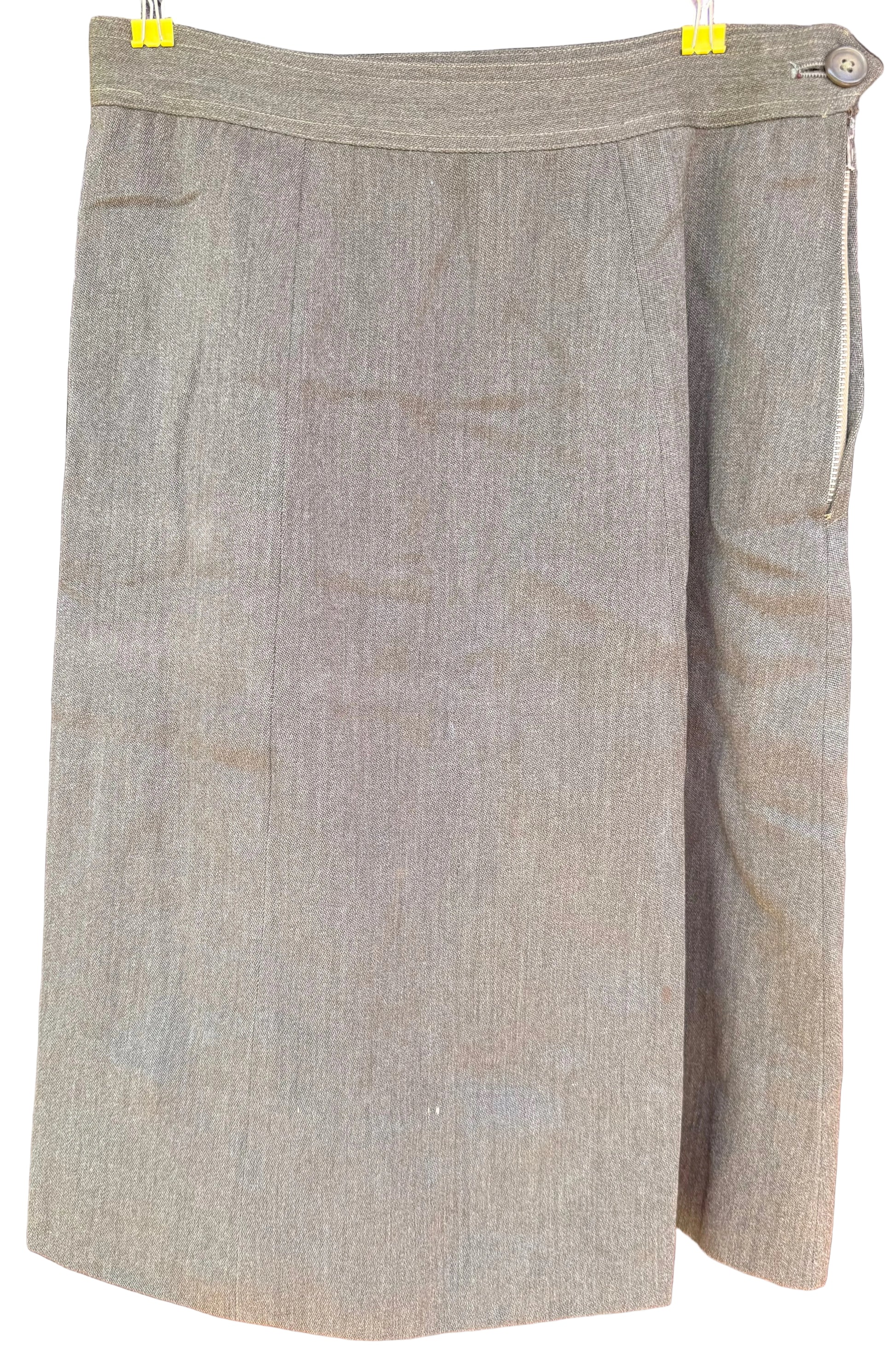 A taupe-beige textured skirt with a wrap-style front and side button closure, hanging on a black hanger against a dark wood background.