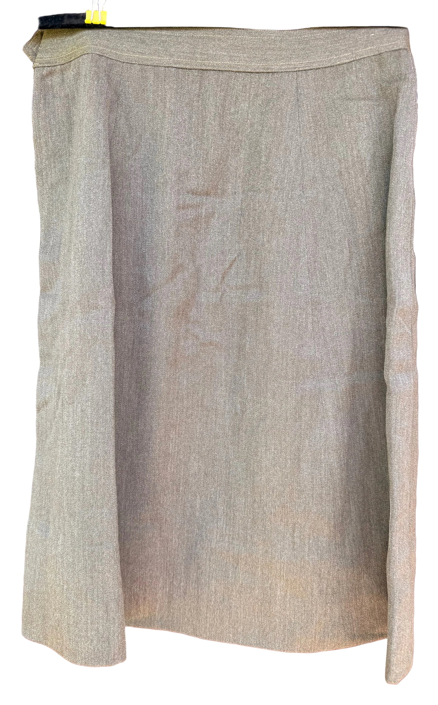A light beige linen skirt hanging on a black hanger against a dark wood background.